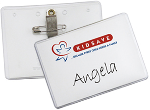 An insert inside a clear badge holder has a red, white and blue logo and a name printed on it. The back of the badge has a pin/clip fastener.