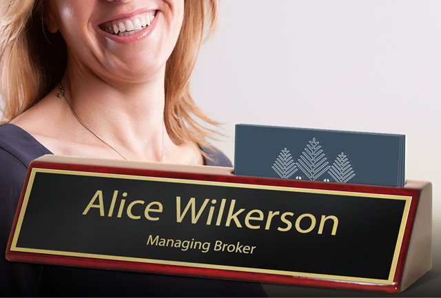 A business person with a customized engraved name plate on an executive desk wedge.