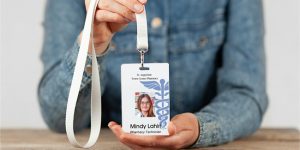 Photo ID Badge with a logo, picture, name and company brand held by an employee on a lanyard.