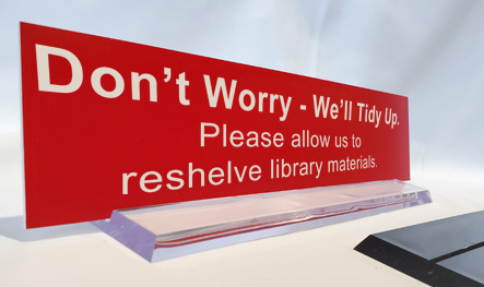 Clear 10 inch plastic desk base being used to display an office sign.