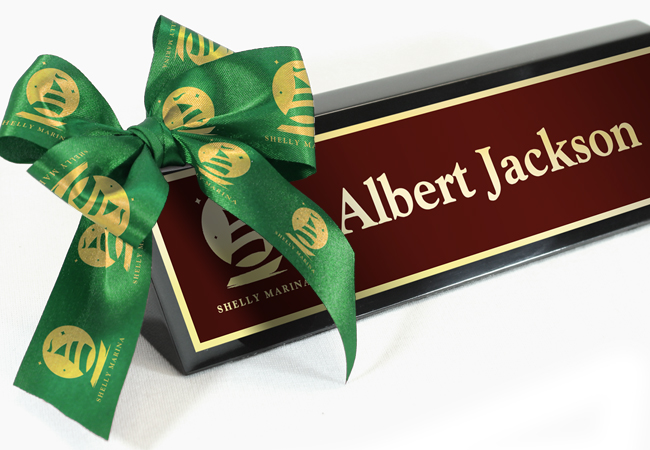 Executive desk wedge with custom engraved name plate with a logo imprinted on a bow created from a ribbon roll.