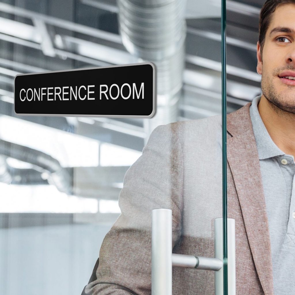 Man opening door with a conference room sign